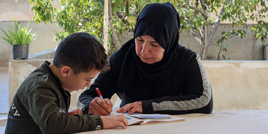 Eine Frau macht mit einem Jungen in Syrien zusammen seine Hausaufgaben Eine Frau macht mit einem Jungen in Syrien zusammen seine Hausaufgaben