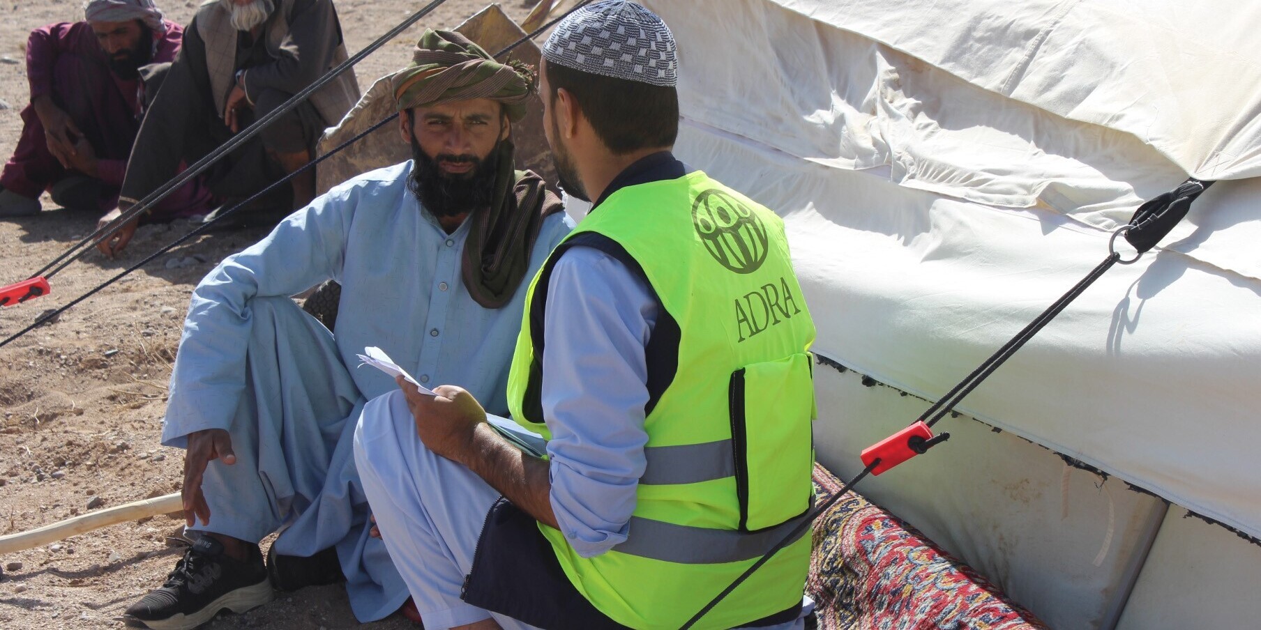 Reza sitzt vor seinem Zelt und spricht mit einem Helfer von ADRA Reza sitzt vor seinem Zelt und spricht mit einem Helfer von ADRA