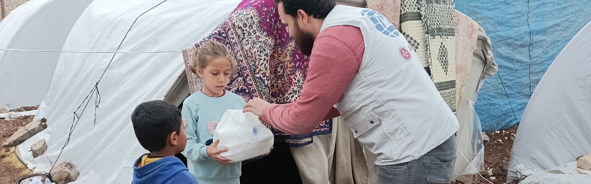 Ein Helfer von einer Partnerorganisation der Johanniter verteilt Lebensmittel an obdachlose Kinder im Erdbebengebiet Türkei-Syrien Ein Helfer von einer Partnerorganisation der Johanniter verteilt Lebensmittel an obdachlose Kinder im Erdbebengebiet Türkei-Syrien