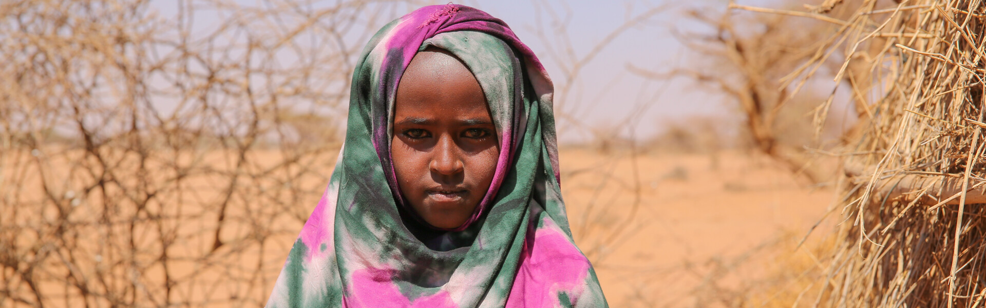 Kind in Somalia hält trockenes Stroh in den Händen. Kind in Somalia hält trockenes Stroh in den Händen.