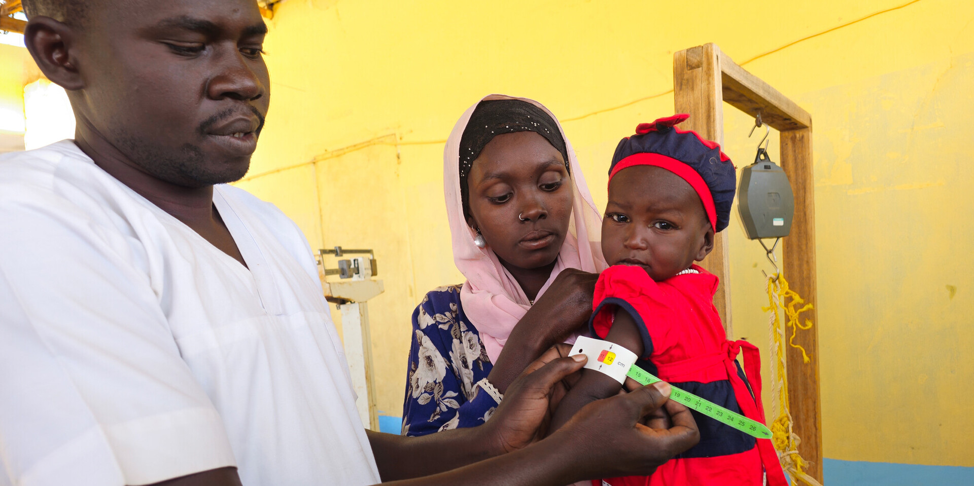 Ein Arzt misst bei einem Kind den Grad der Unterernährung mit dem Hungermaßband Ein Arzt misst bei einem Kind den Grad der Unterernährung mit dem Hungermaßband