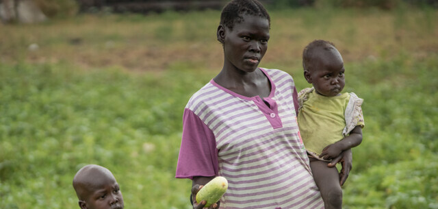 Mutter trägt ihr Kind im Südsudan über das Gurkenfeld Mutter trägt ihr Kind im Südsudan über das Gurkenfeld