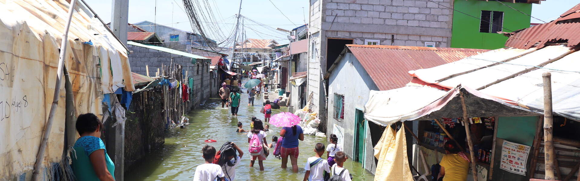 Menschen auf den Philippinen waten durch eine überschwemmte Seitenstraße Menschen auf den Philippinen waten durch eine überschwemmte Seitenstraße