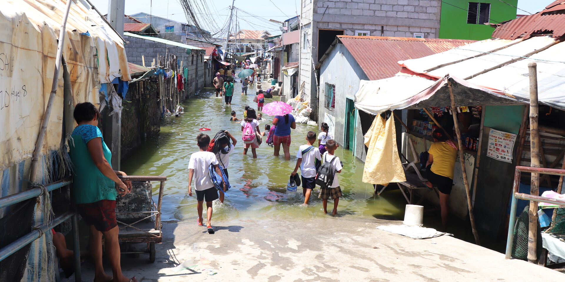 Menschen auf den Philippinen waten durch eine überschwemmte Seitenstraße Menschen auf den Philippinen waten durch eine überschwemmte Seitenstraße
