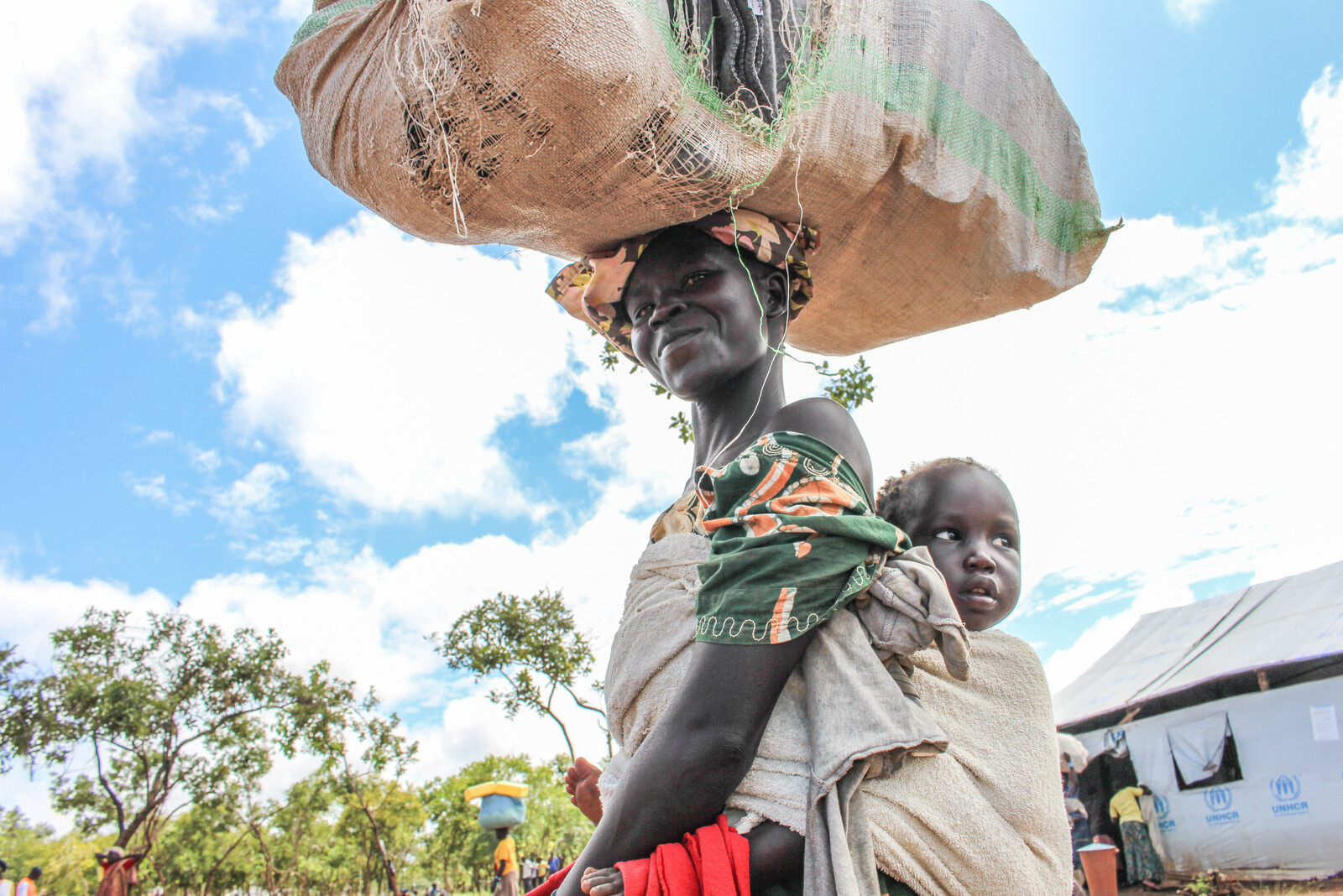 Frau mit Kind in Uganda, wo Hilfsorganisation Nahrungsmittel an Menschen verteilt hat, die von Hunger betroffen sind