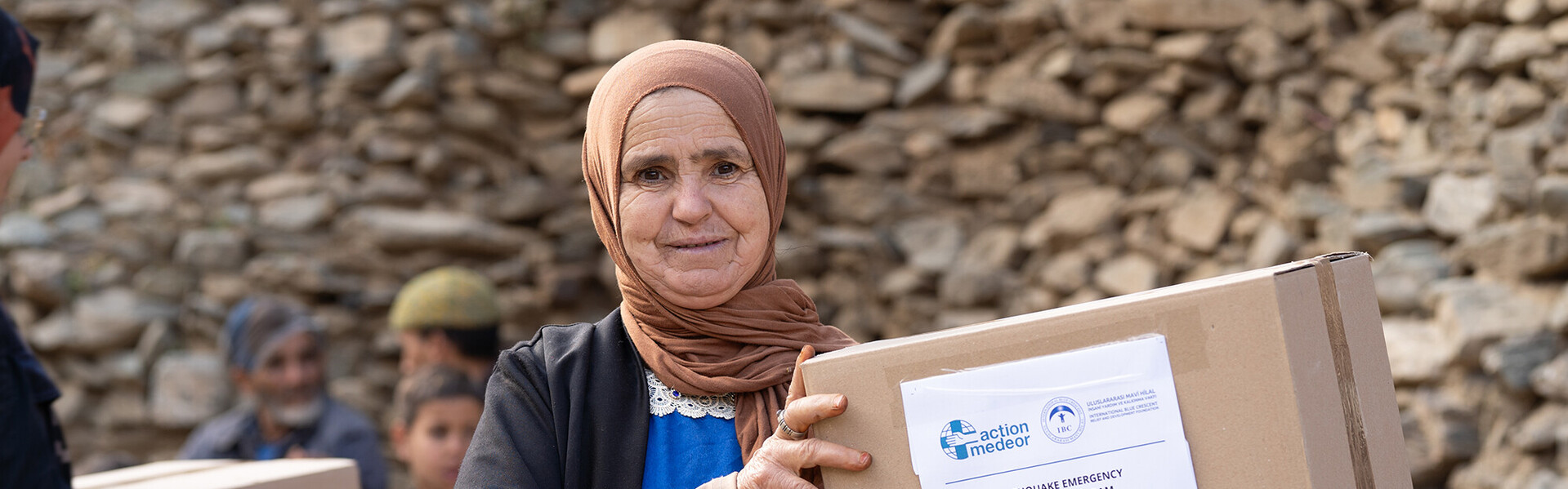 Direkt nach dem Erdbeben in Marokko schickt action medeor Hilfspakete in die schwer getroffene Bergregion Eine Frau mit Kopftuch hält ein Paket mit einer Hilfslieferung von action medeor in der Hand